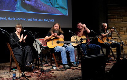 Musicians with guitars performing on stage at the tribute program